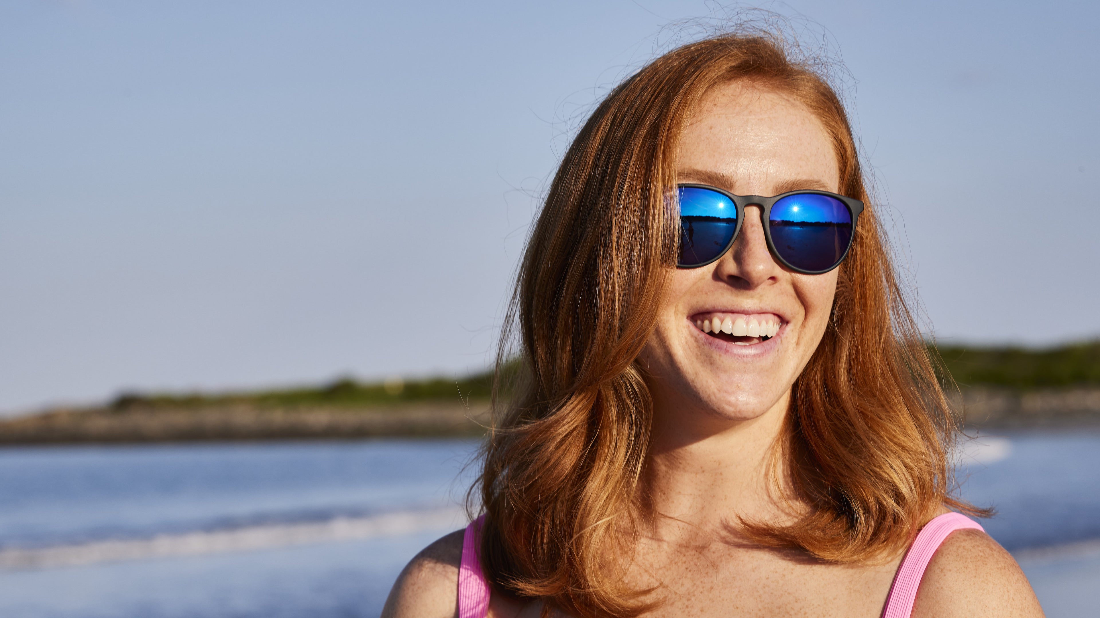 women wearing blue sunglasses in the sun smiling